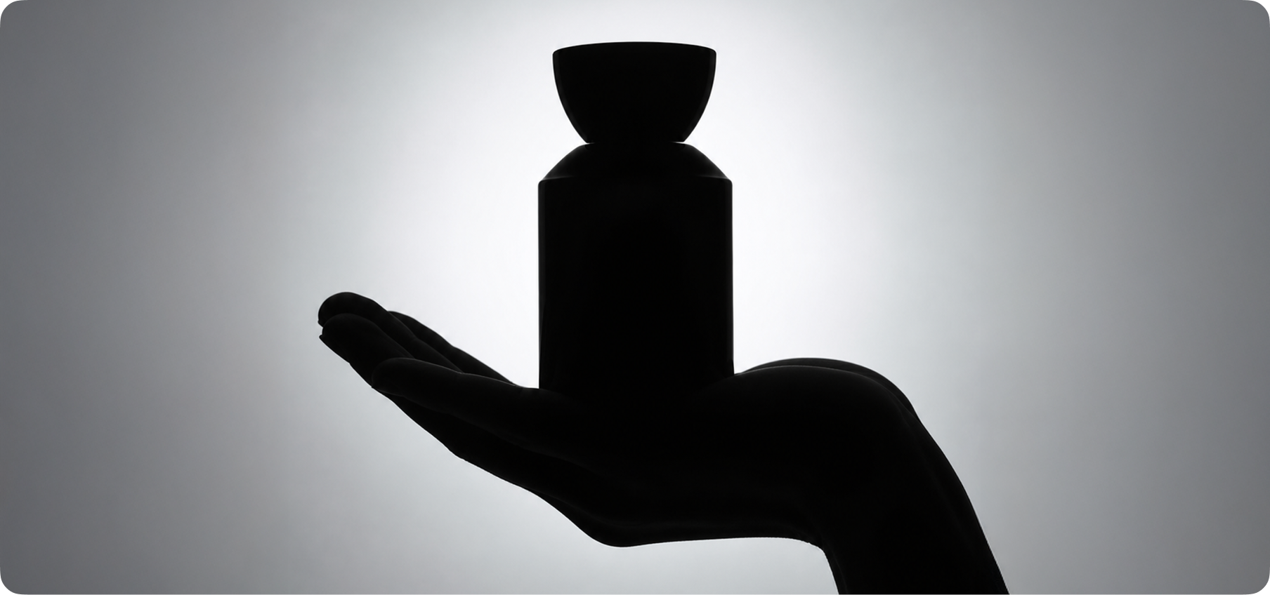 A hand cradling a Rouge & Tate fragrance bottle in dramatic light — the naming-first approach behind the brand, devotion as the central idea