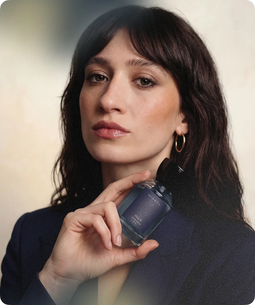 Model holding a beauty product against a dark background