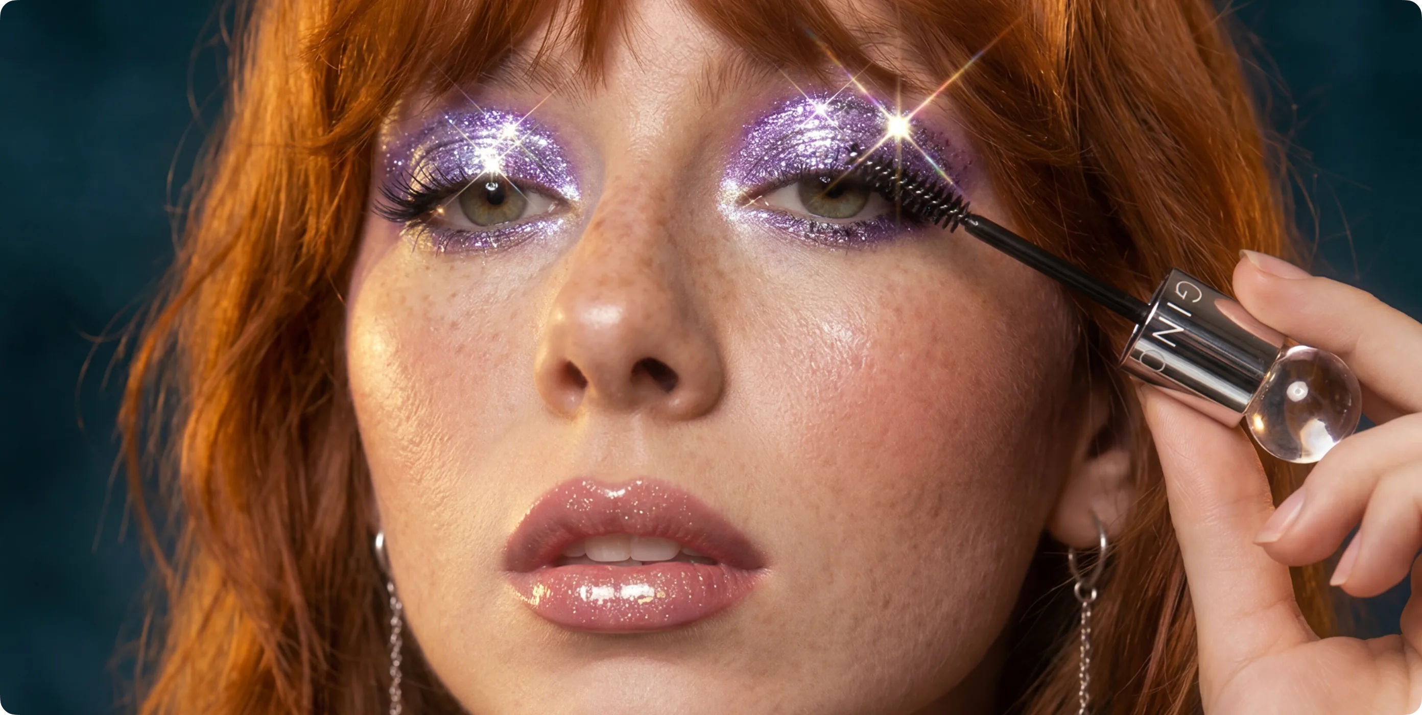 Closeup portrait of a model applying mascara with purple glitter eye makeup