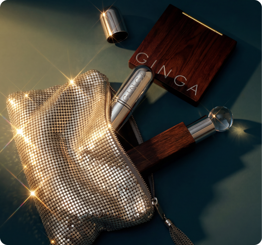 Ginga — flat-lay of the wood-veneer and chrome lipstick and applicators beside a gold sequined clutch on a deep-teal surface with sparkle