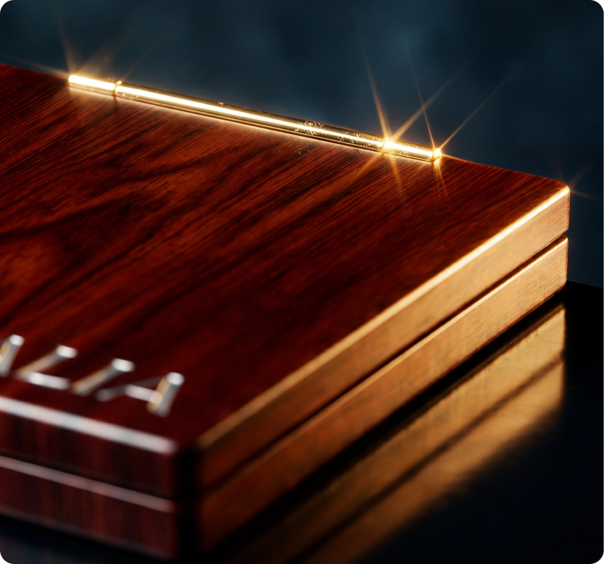 Ginga — macro detail of the polished wood-veneer compact edge embossed with the GINGA wordmark, catching golden light on a dark reflective surface