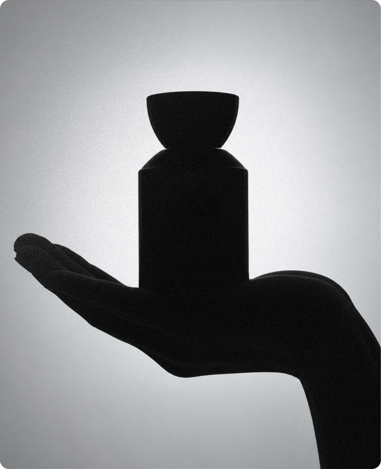 Rouge & Tate — high-contrast silhouette of a hand cradling a bottle against a grainy grey backlight