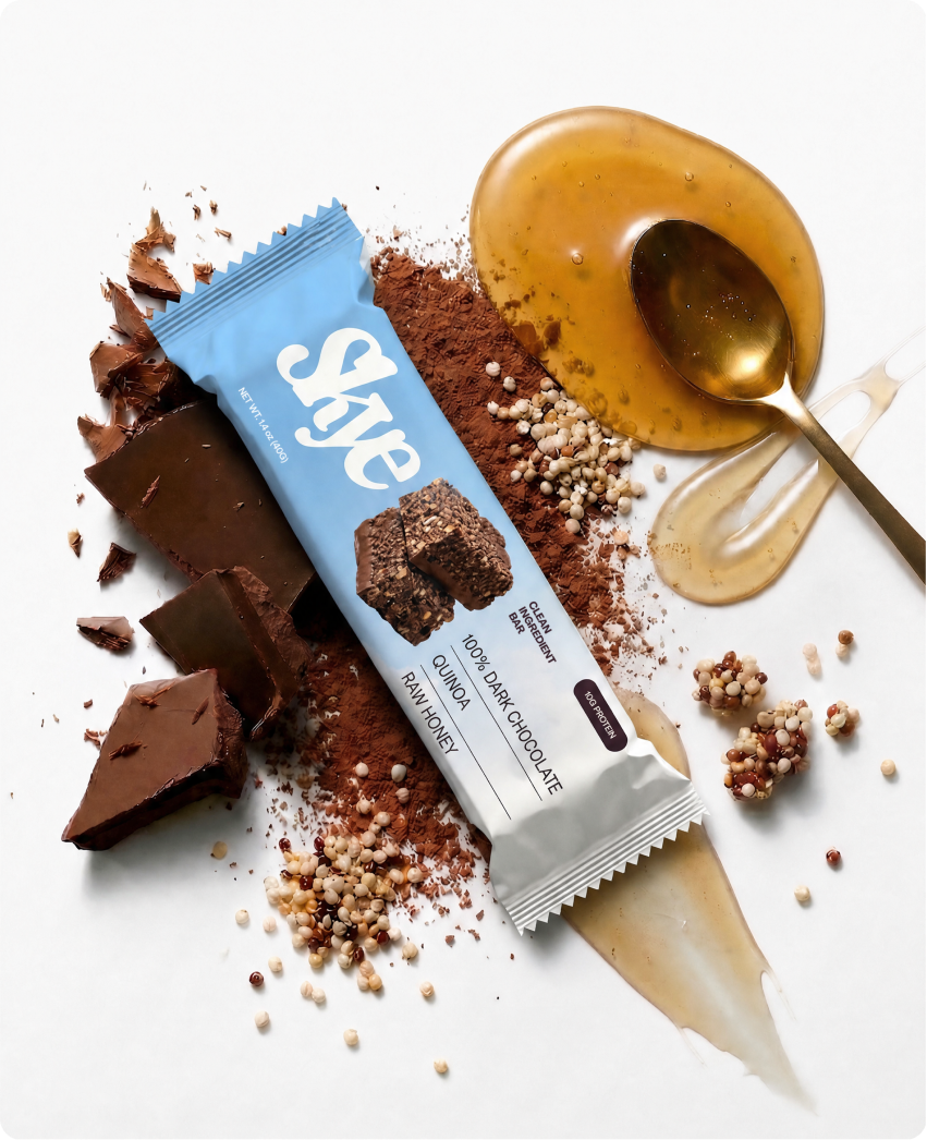 Skye — a protein bar standing upright among dark chocolate chunks, cacao powder, and a golden spoon of raw honey