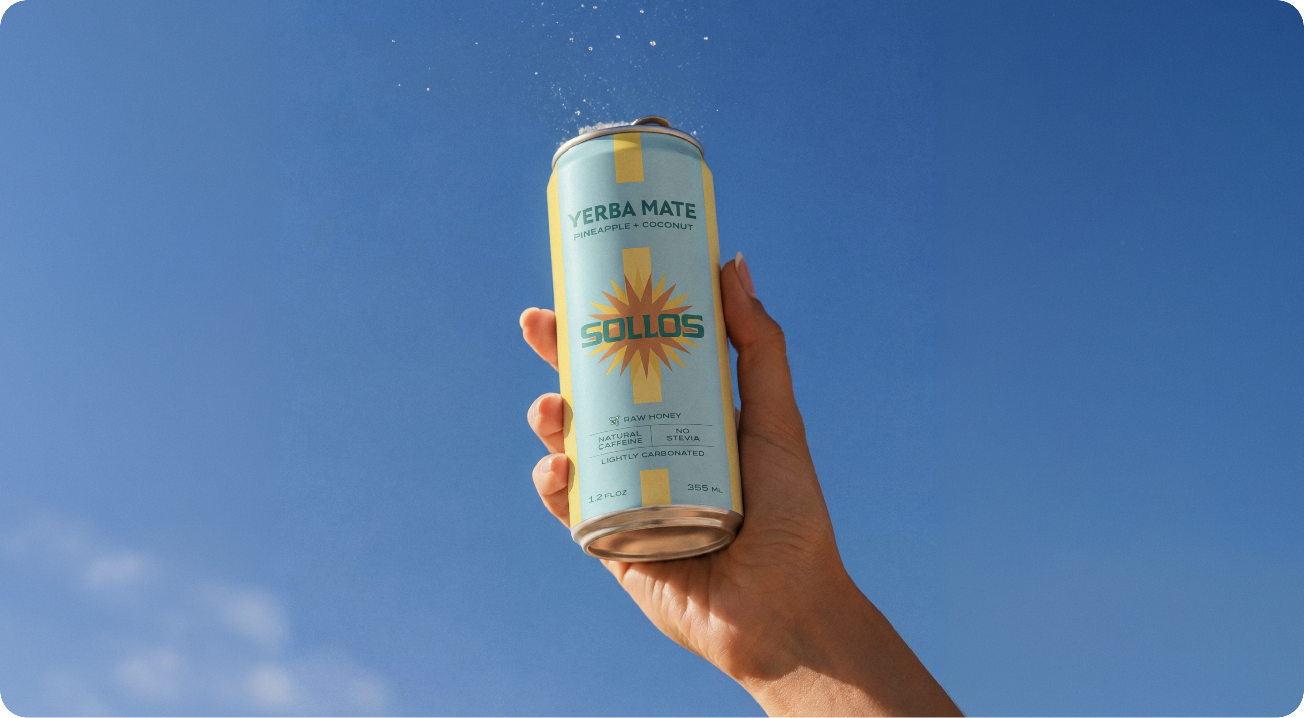 Sollos — a hand holding a Sollos yerba mate can aloft against a clear blue sky with a splash of liquid