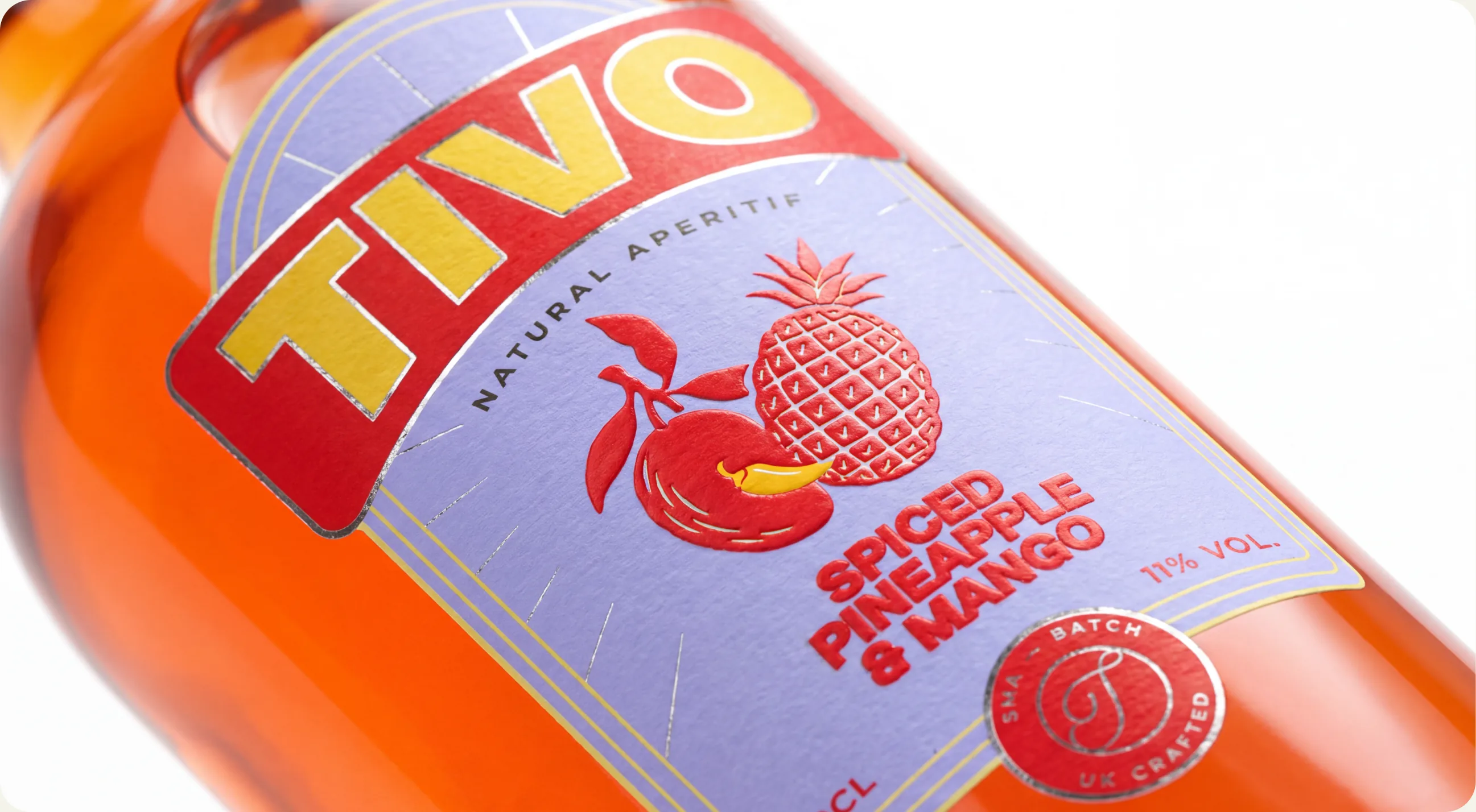 Tivo: a macro of the Spiced Pineapple and Mango label on the orange bottle, the Tivo wordmark large above the illustrated pineapple and chilli