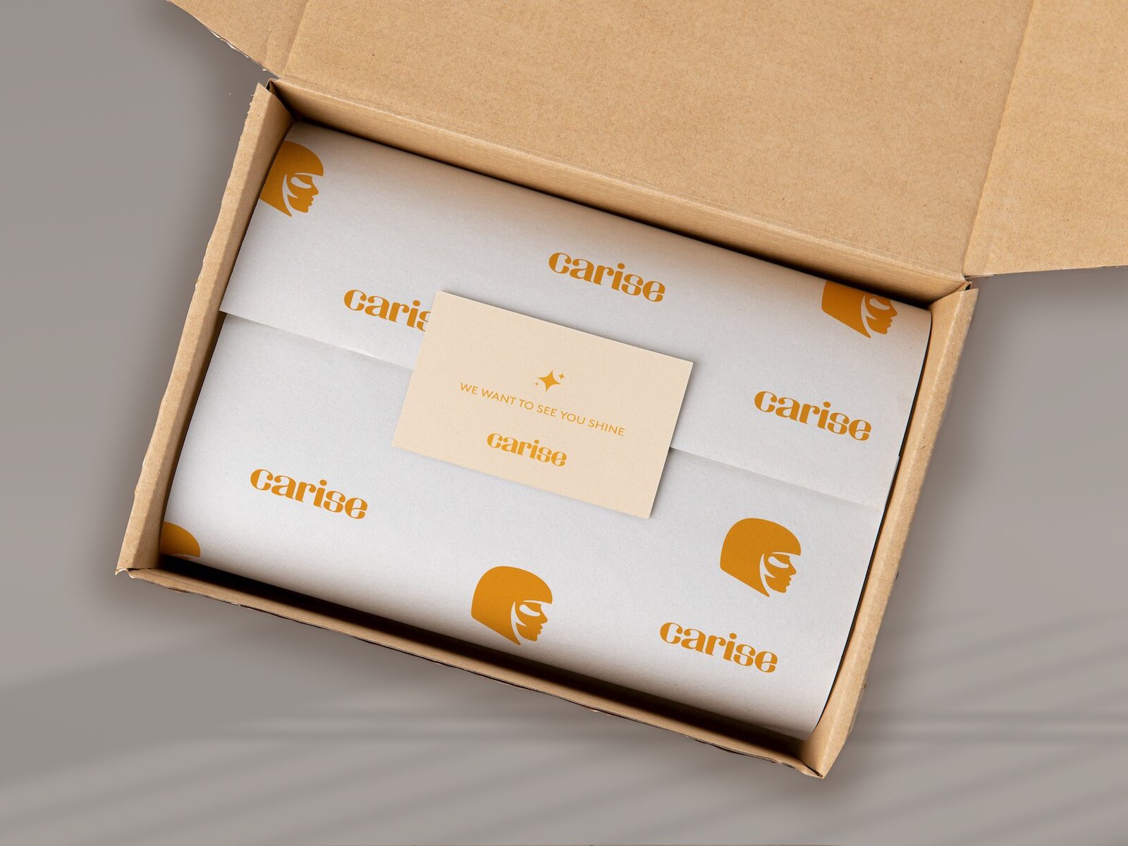 packaging box made of cardboard, white wrapping paper with logo and brand name. Card inside with quote that reads "We want to see you shine"