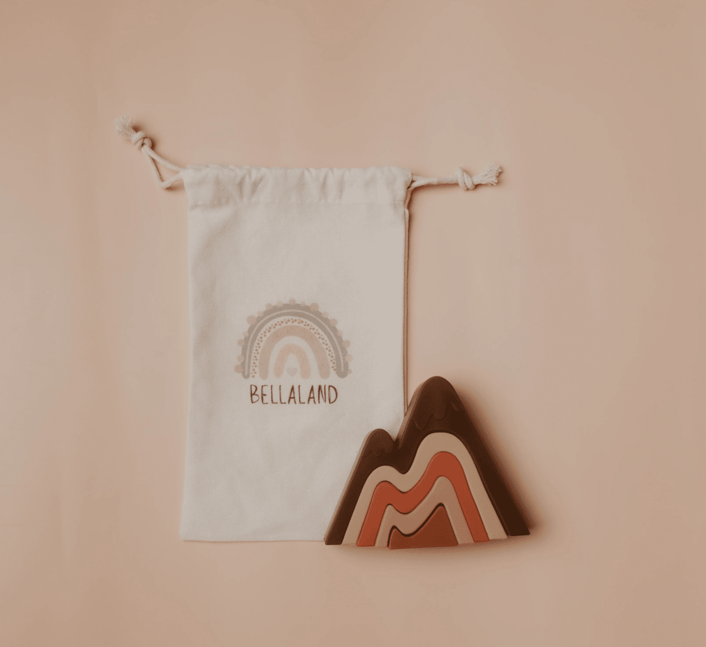 small white cloth bag, with brand logo and name printed. And small baby toy in mountain shape